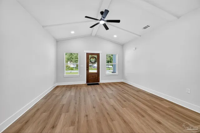 an empty room with wooden floor and windows