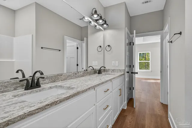 a bathroom with a granite countertop double vanity sink mirror and shower