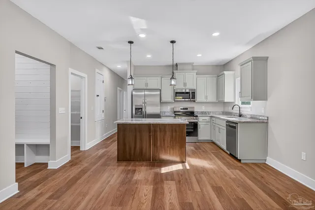 a kitchen with kitchen island granite countertop a sink cabinets and wooden floor