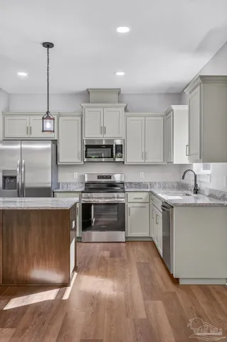 a kitchen with stainless steel appliances granite countertop a sink a stove a refrigerator and white cabinets