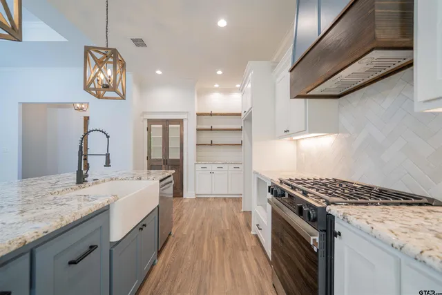 a kitchen with granite countertop a sink stainless steel appliances and cabinets