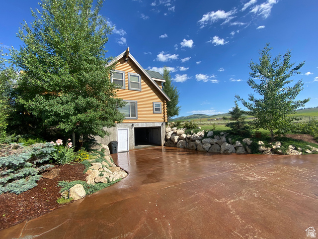 79 Auburn Forest Road Auburn, WY 83111 - Photo 6 of 76 View of property exterior featuring driveway, an attached garage, a metal roof, and log siding