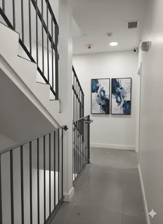 a view of staircase with lots of frames on wall and a view of a kitchen