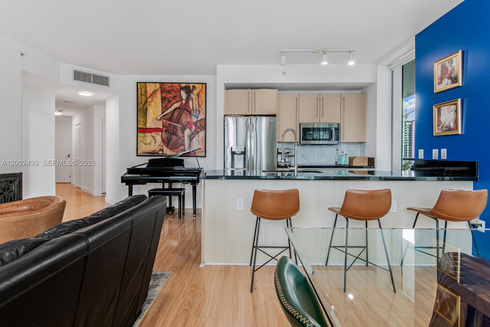 79 Southwest 12th Street, Unit 2107S Miami, FL 33130 - Photo 12 of 47 a kitchen with stainless steel appliances kitchen island granite countertop a table chairs in it and wooden floors