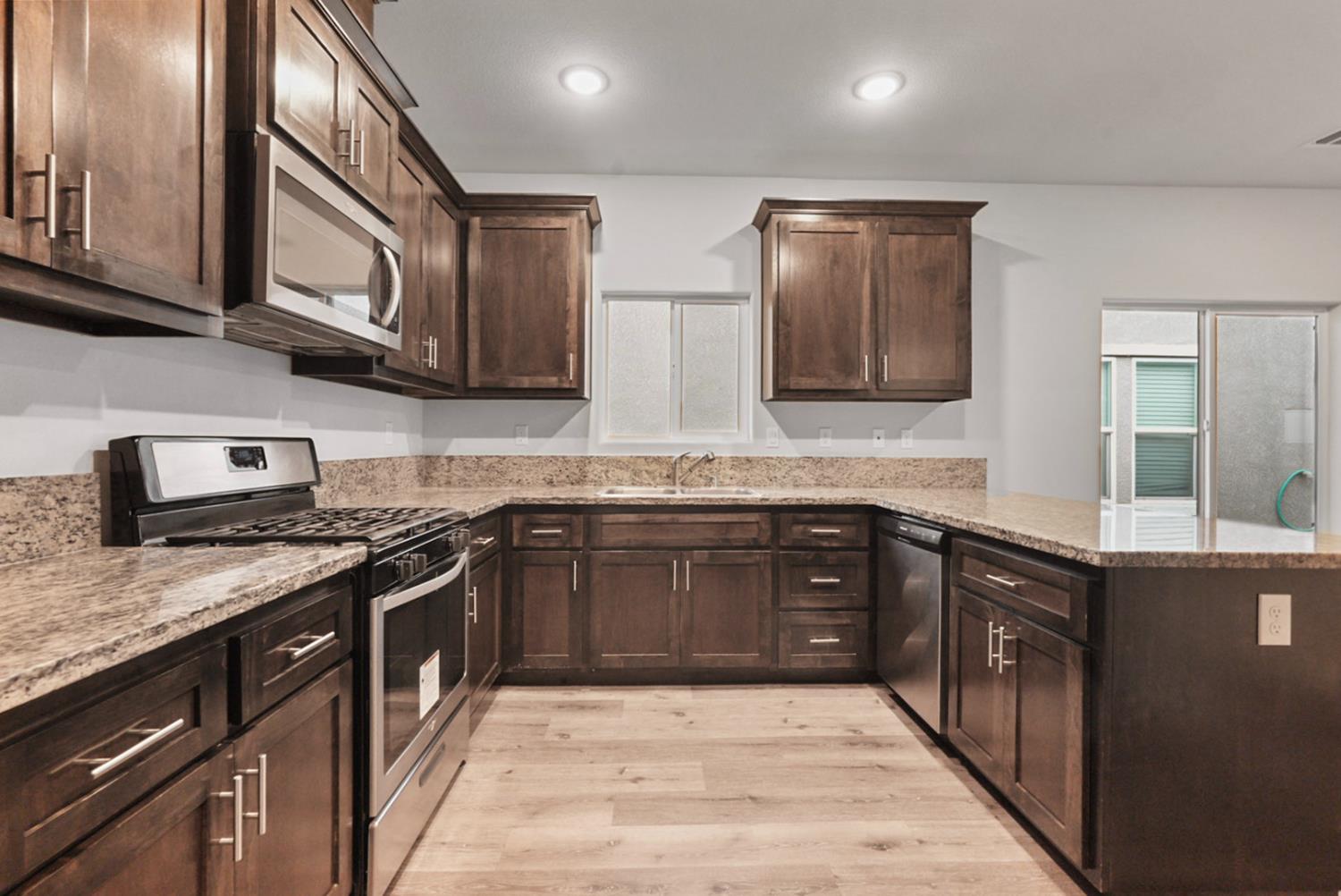 683 Granada Court Merced, CA 95341 - Photo 4 of 9 a kitchen with stainless steel appliances granite countertop wooden cabinets a stove top oven and granite counter tops