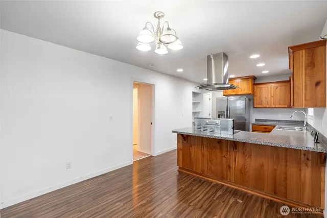 a view of a kitchen with granite countertop wooden floor and stainless steel appliances