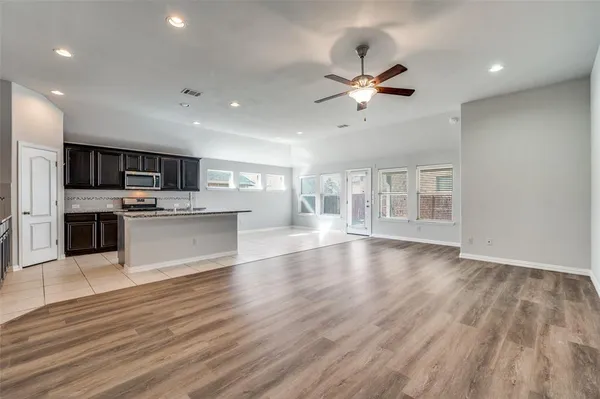 a view of an empty room with kitchen appliances and a ceiling fan