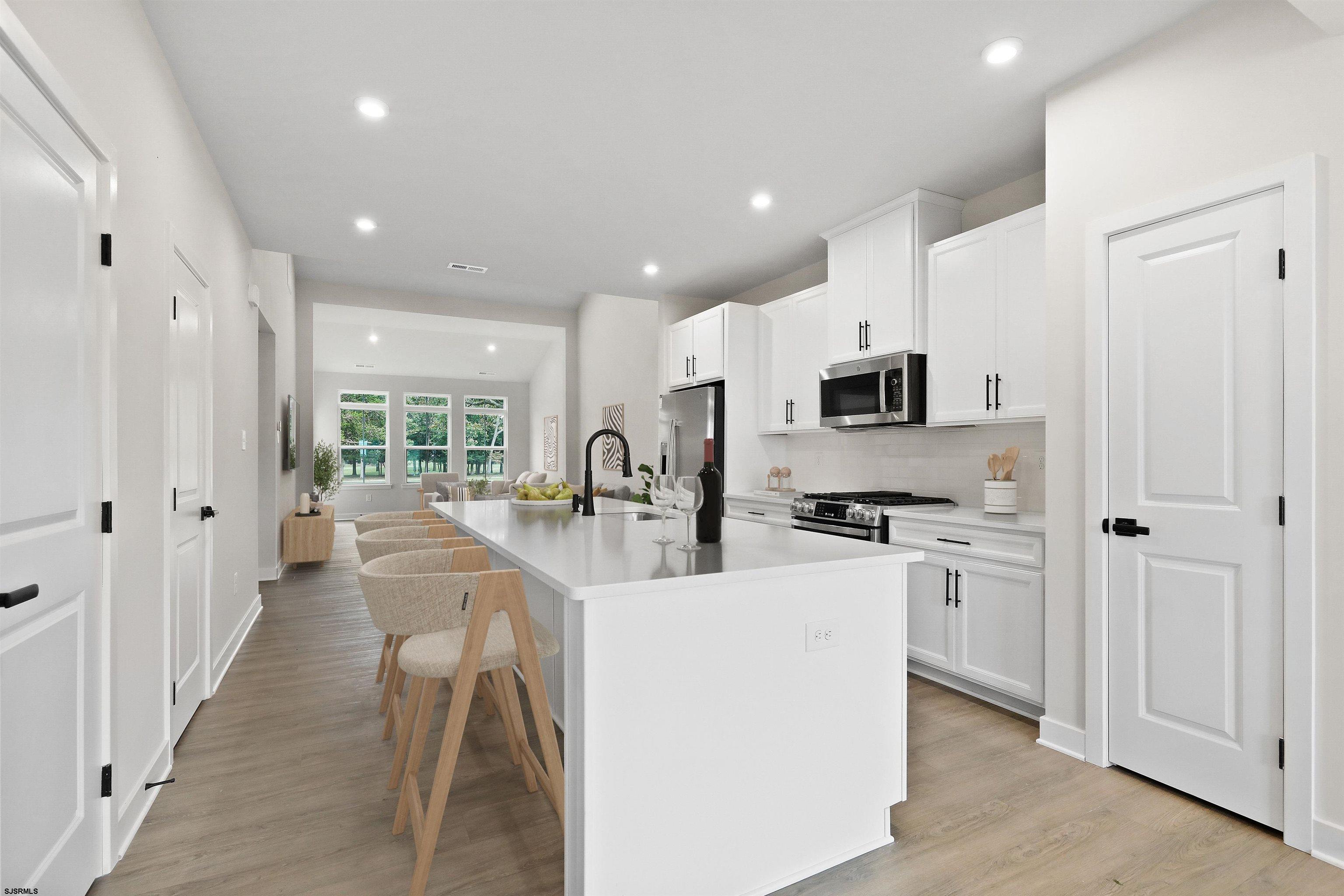 705 Jesse Drive, Unit 705 Somers Point, NJ 08244 - Photo 3 of 15 a kitchen with stainless steel appliances kitchen island granite countertop a refrigerator oven a sink dishwasher and white cabinets with wooden floor