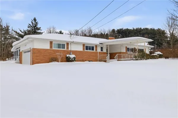 a front view of a house with a yard covered in snow
