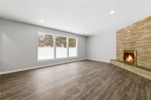 an empty room with wooden floor and a fireplace