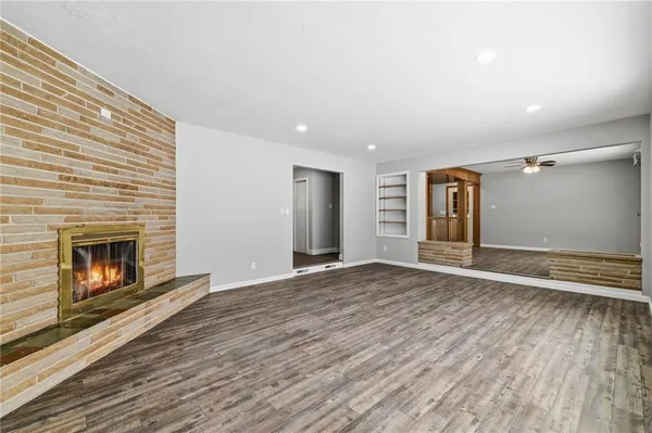 a view of an empty room with wooden floor fireplace and a window
