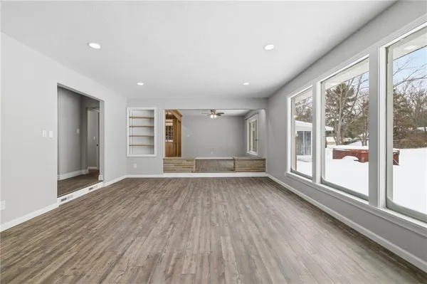 a view of an empty room with a window and wooden floor