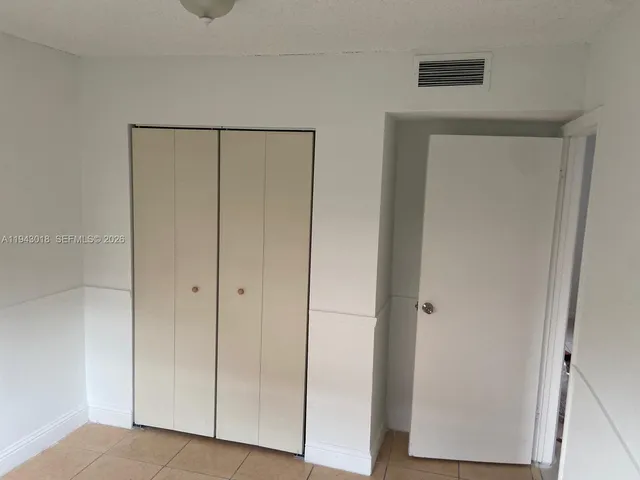 a view of an empty room with closet and a hallway