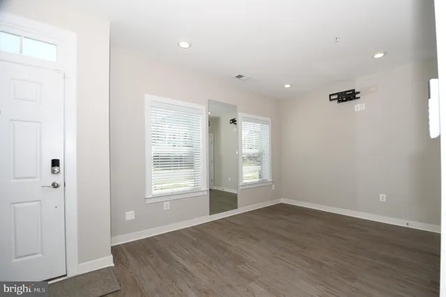 an empty room with wooden floor and windows