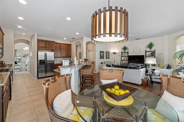 a kitchen with stainless steel appliances granite countertop a stove top oven a sink a dining table and chairs with wooden floor