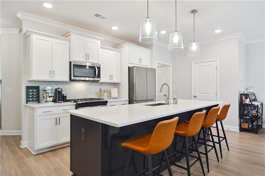 765 Trevett Way Marietta, GA 30066 - Photo 5 of 44 a open kitchen with stainless steel appliances granite countertop a stove a refrigerator a kitchen island a sink white cabinets and couches with wooden floor