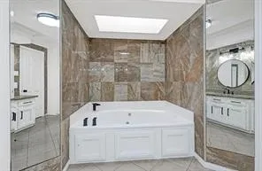 a bathroom with a tub a sink and a mirror