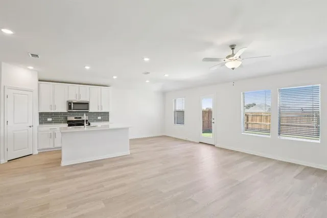 a view of kitchen with stove and white cabinets with wooden floor