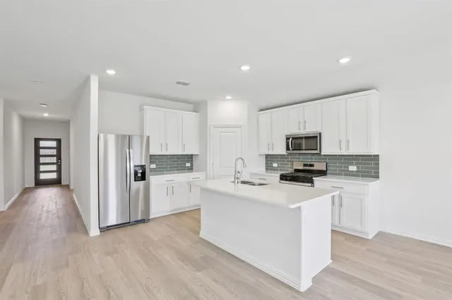 a kitchen with white cabinets and stainless steel appliances