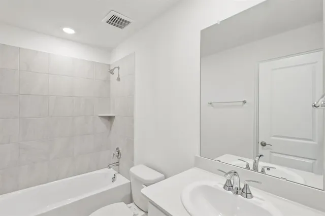 a bathroom with a bathtub shower sink vanity and a toilet
