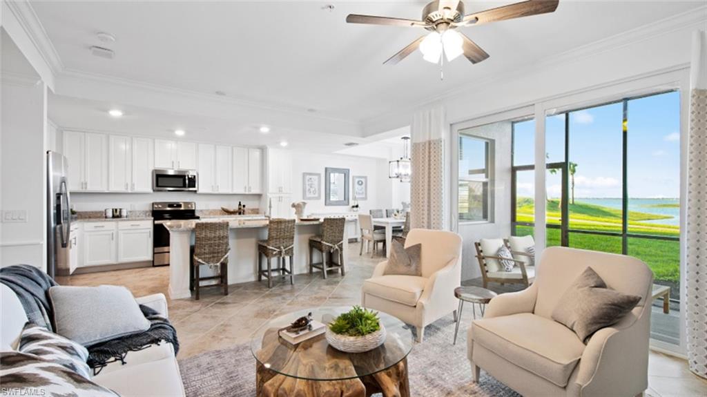 Living room featuring ceiling fan with notable chandelier, light tile patterned floors, and ornamental molding