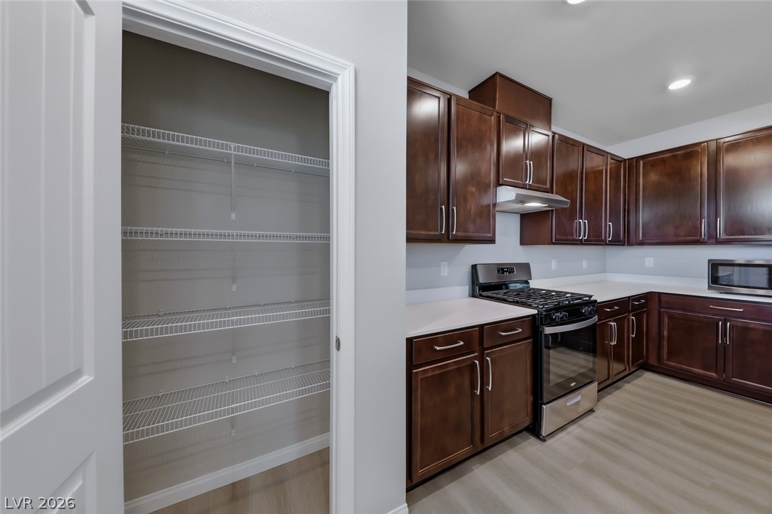 3564 Credere Lane Henderson, NV 89074 - Photo 11 of 40 Kitchen featuring stainless steel appliances, light countertops, dark wood finish cabinets, and light wood finished floors