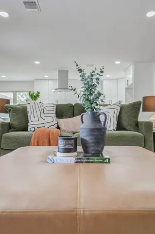 a living room with furniture potted plant and kitchen view
