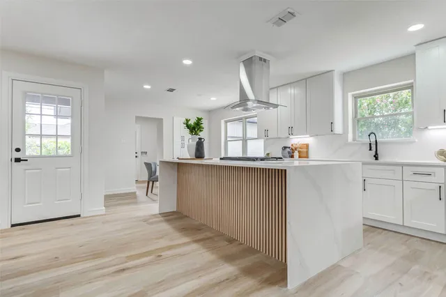 a kitchen with kitchen island white cabinets and wooden floor