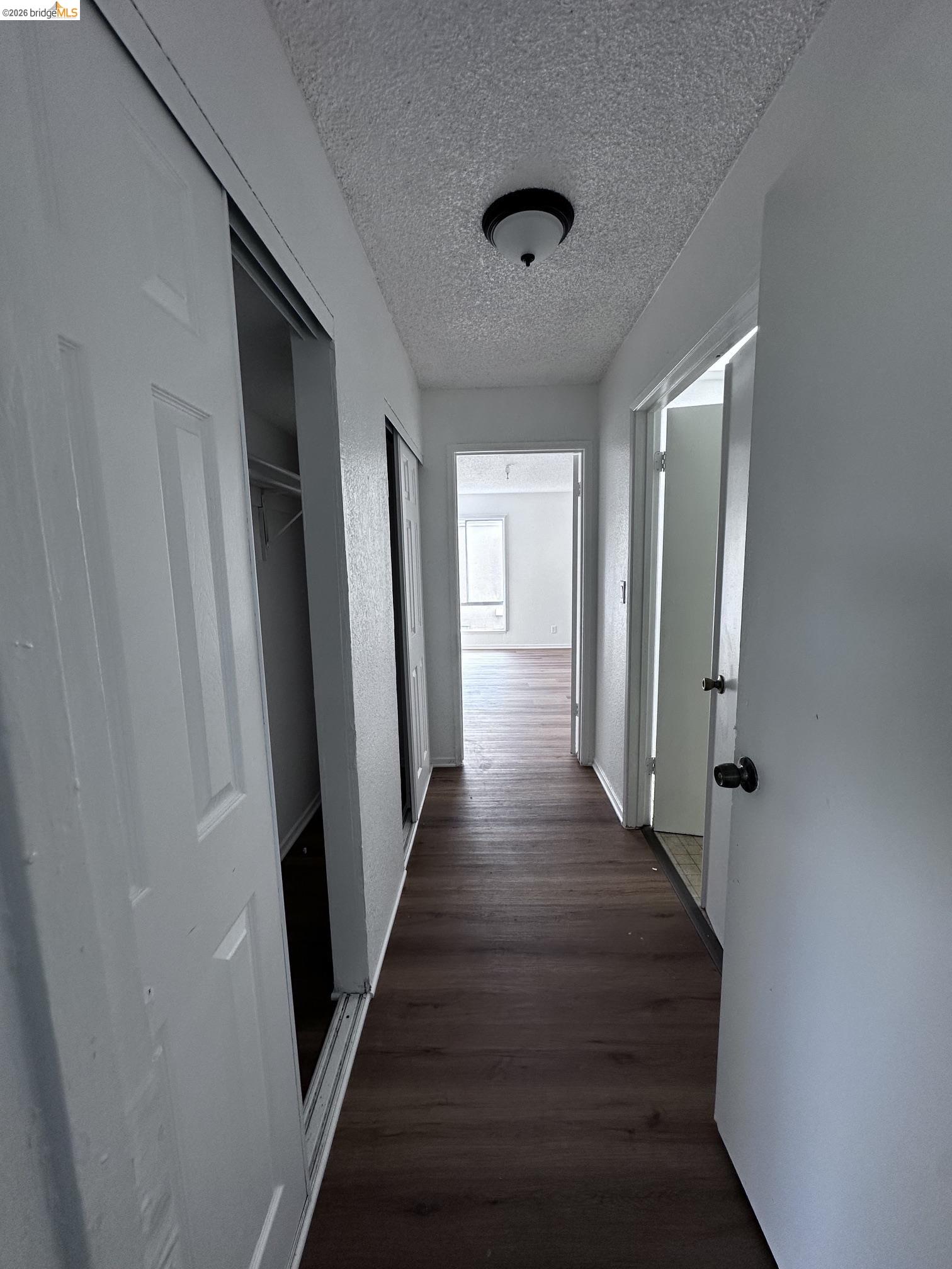 2121 Vale Road, Unit 17 San Pablo, CA 94806 - Photo 11 of 17 Hallway featuring wood-finish flooring, white paneled doors, and a ceiling-mounted light fixture