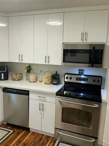 a view of kitchen and empty room with wooden floor