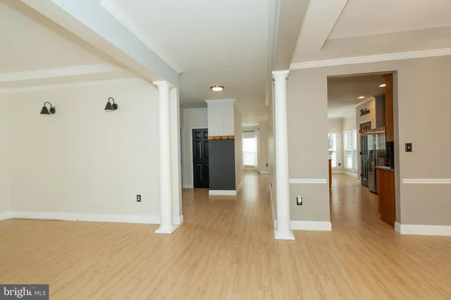 a view of a hallway with wooden floor and a bathroom