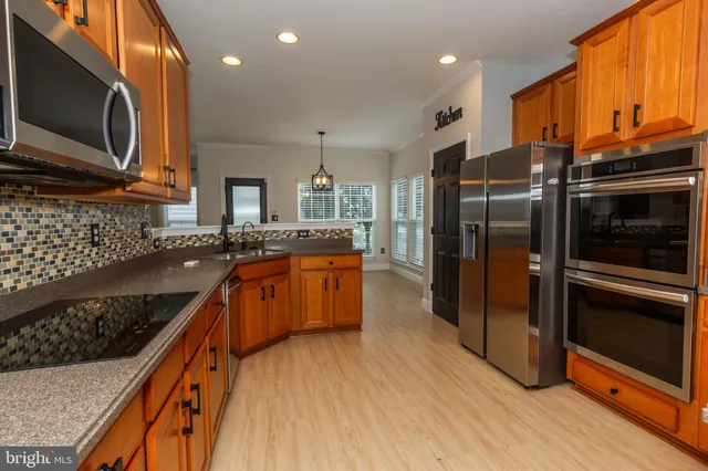 a kitchen with stainless steel appliances granite countertop a refrigerator a stove top oven and sink