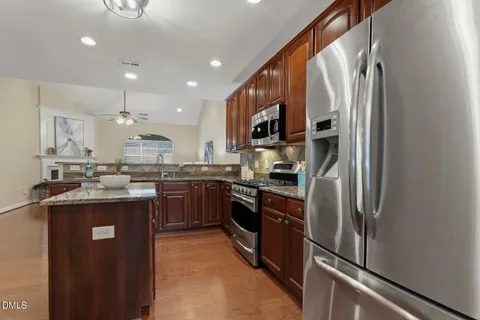 a kitchen with granite countertop stainless steel appliances wooden cabinets and a stove top oven