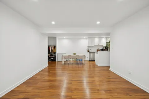 a view of dining room with kitchen island stainless steel appliances wooden floor and a window