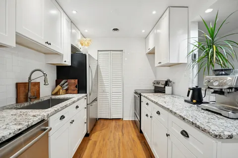 a kitchen with granite countertop a sink a stove and cabinets
