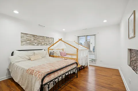a spacious bedroom with a bed a mirror and wooden floor