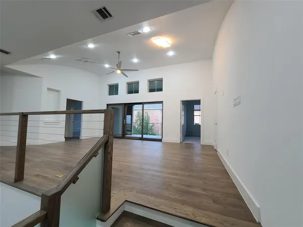 a view of a big room with wooden floor and windows