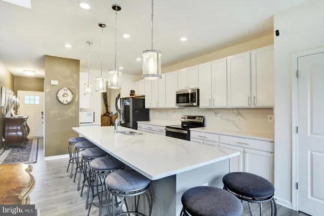 a kitchen with stainless steel appliances a dining table chairs stove top oven and refrigerator