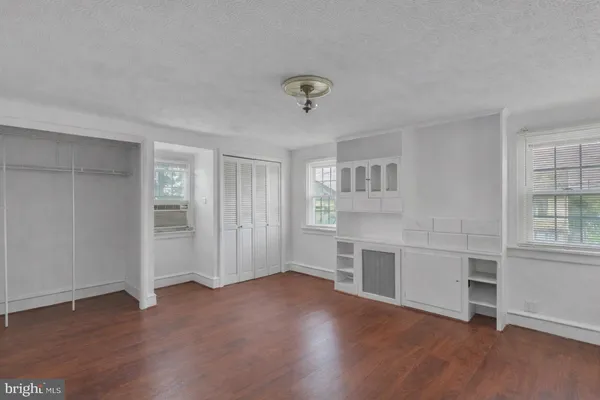 an empty room with windows and cabinet