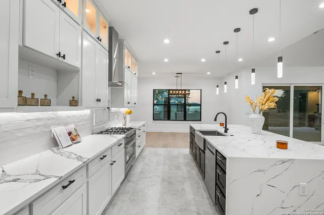 a large white kitchen with a large counter top appliances and cabinets