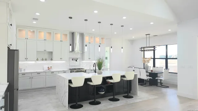 a large kitchen with lots of counter space white cabinets and stainless steel appliances