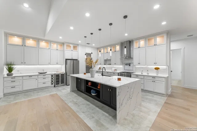 a kitchen with stainless steel appliances kitchen island granite countertop a sink counter space cabinets and a large window