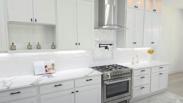 a kitchen with white cabinets and a stove with wooden floor