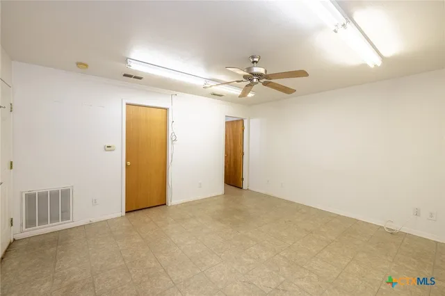 an empty room with a ceiling fan and a window