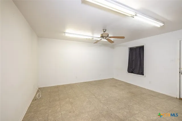 an empty room with windows and fan