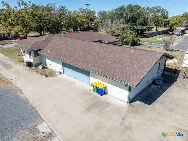 an aerial view of a house with swimming pool and large trees