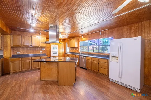 a kitchen with stainless steel appliances a refrigerator and wooden floors