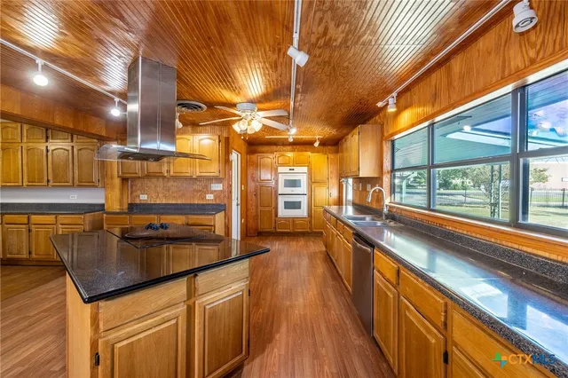 a kitchen with stainless steel appliances granite countertop a sink and wooden cabinets