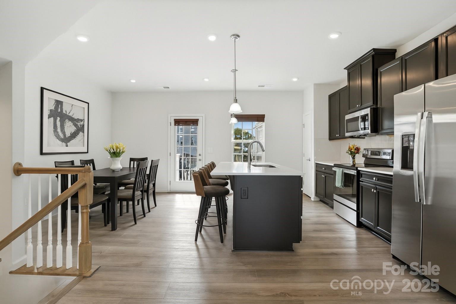 2108 Trout Lily Lane, Unit 198 Matthews, NC 28104 - Photo 15 of 45 a open kitchen with stainless steel appliances granite countertop a refrigerator a stove top oven a sink dishwasher a dining table and chairs with wooden floor