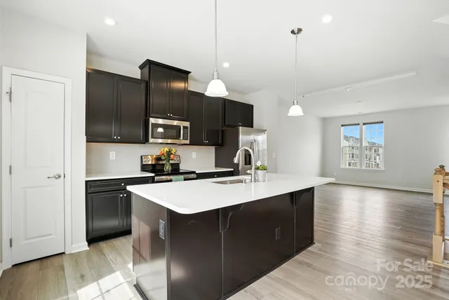 a kitchen with stainless steel appliances granite countertop a refrigerator a sink dishwasher a stove and a microwave oven on granite countertops